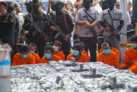 Petugas menunjukkan barang bukti cairan mengandung metamfetamin dan rokok ilegal yang diamankan dari kapal MV OCEAN PORTER di Perairan Karimun. (Foto: BNN RI).