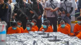 Petugas menunjukkan barang bukti cairan mengandung metamfetamin dan rokok ilegal yang diamankan dari kapal MV OCEAN PORTER di Perairan Karimun. (Foto: BNN RI).